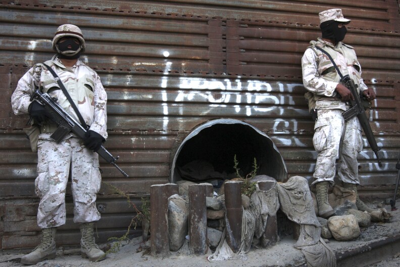 File-This June 4, 2010 file photo shows Mexican army soldiers standing guard next to a tunnel at the border wall in Tijuana, Mexico. More than 75 such underground passages have been found along the border since 2008, concentrated largely in California and Arizona. The job of searching these networks can be dangerous, so the U.S. Border Patrol is unveiling its latest technology in the underground war,  a wireless, camera-equipped robot that can do the job in a fraction of the time. (AP Photo,File)