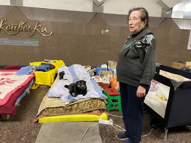 Laura Sakolova, 75, poses with her dog, Mafia, in the Oleksiivska station, where she lives with one of her grandsons. Sakolova's daughter and youngest grandchild recently moved out of the metro because the toddler developed persistent eye infections.