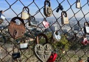 Different type of security locks hanging on a chain link fence with a background view of downtown Los Angeles.