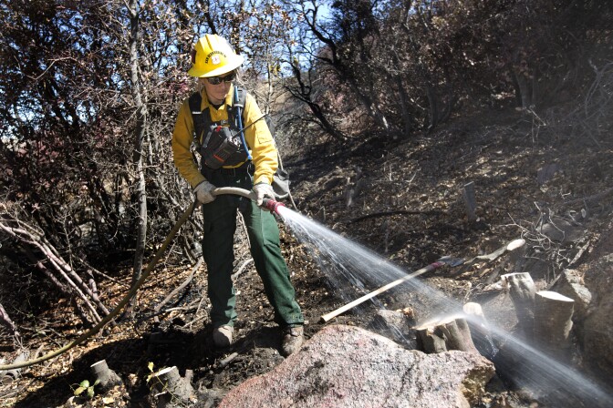 Firefighter Nicole White works tp protect a home from the Pilot Fire burning in Hesperia, California on August 9th, 2016.
