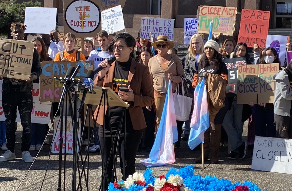 Melissa Camacho-Cheung, senior staff attorney with the ACLU of Southern California, called on LA County Supervisors to commit to a timeline to close Men's Central Jail at a rally on March 30, 2023.  Camacho-Cheung wears a black t-shirt and pants with a brown blazer and speaks into a microphone. 