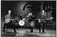 Black and white photo of four musicians playing on stage at American Bandstand.