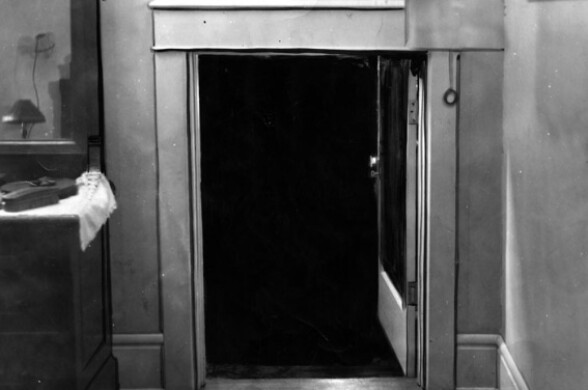 A small door to an attic space is pictured in black and white.