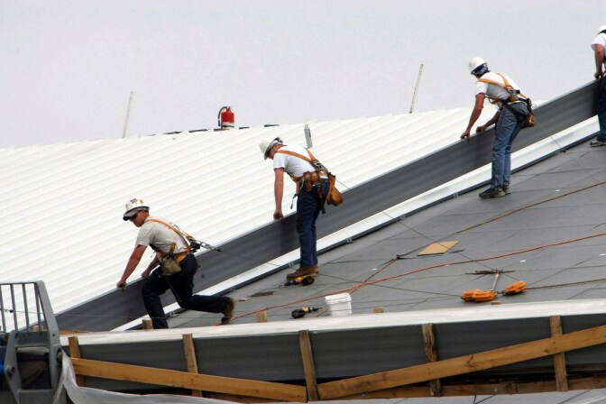 Workers install a cool roof. Usually white or light colored, they can be up to 55 degrees cooler than regular roofs. 