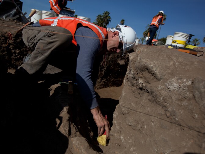 Archaeologist Henry Chodsky clears dust from the wall of an adobe house discovered in an excavation near the San Gabriel Mission.