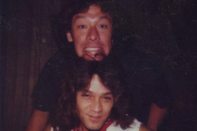 A photograph of two people with one's head on top of the other's as they pose