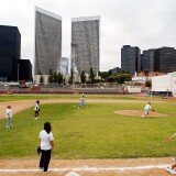 Students at Beverly Hills High School play softball within sight of an oil well tower (L) covered in flower designs May 7, 2003 in Beverly Hills, California.
