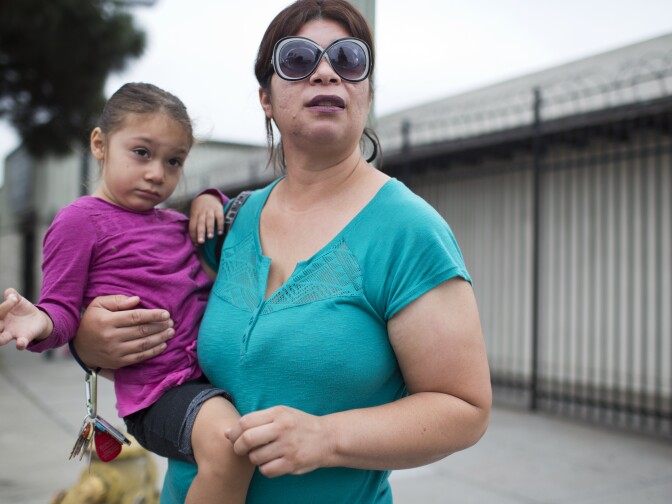 Sara Cornejo, right, and her three-year-old daughter, Madeline, wait to cross South Broadway before catching a bus to Cornejo's mother's house on Friday, August 21, 2015 in South Los Angeles.