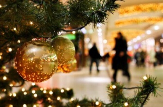 Christmas shoppers walk past a decorated Christmas tree at a shopping mall.