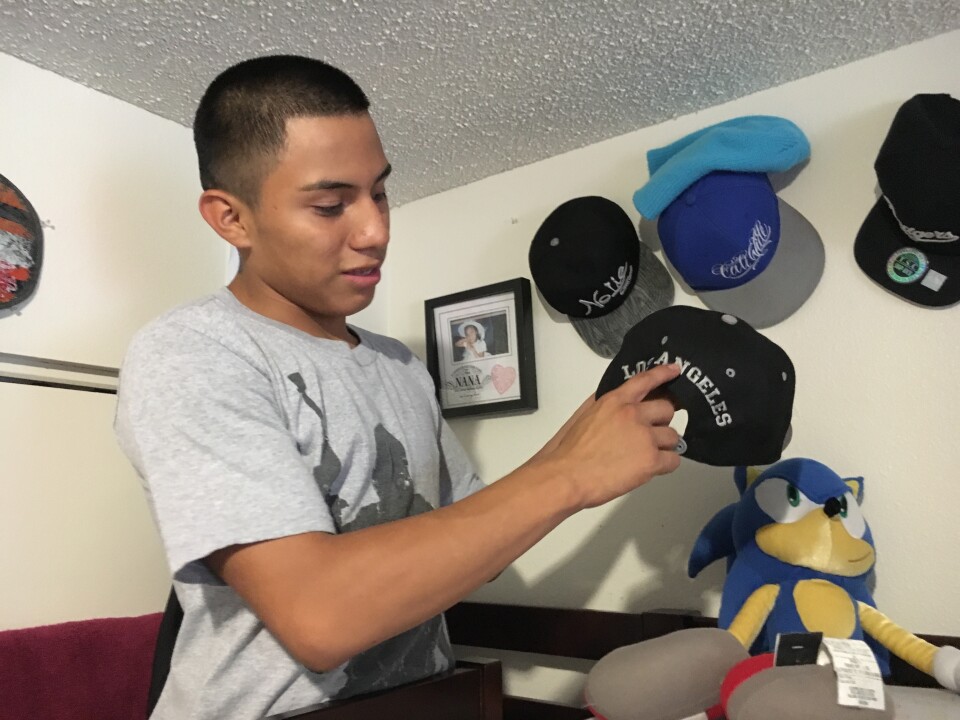 Luis Gonzalez, 16, shows off his baseball hat collection in his room. He was granted asylum, along with his brother, Alejandro, in 2015.