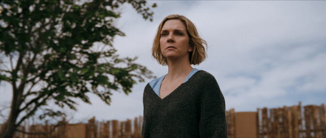 A photo still from a TV show with a white woman standing somewhere outside.