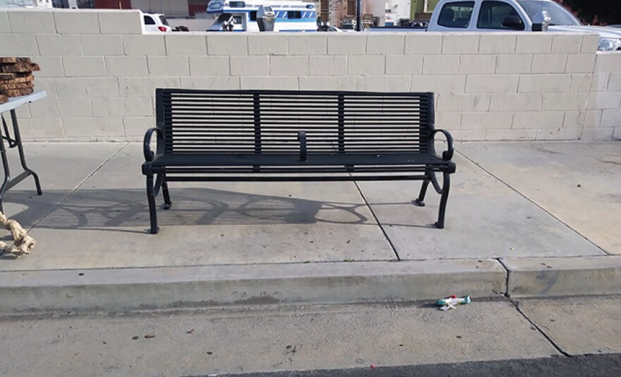 An empty green bench with bar in the middle.