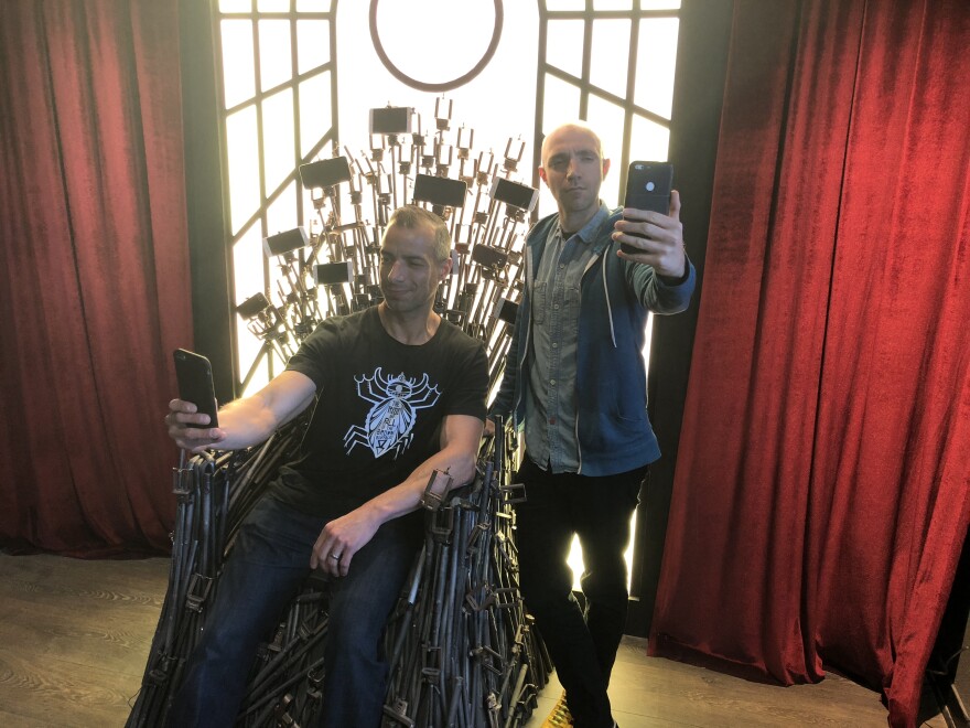 A Martinez and Tommy Honton take a selfie on the selfie throne made of selfie sticks.