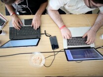 MIAMI, FL - FEBRUARY 01:  Miguel Chateloin  (L) and Lazaro Gamio use their computers to write code that would allow people living in Cuba to use email to post to blogs during the Hackathon for Cuba event on February 1, 2014 in Miami, Florida.  The hackathon brought together experts and programmers to devise innovative technology solutions aimed at strengthening communications and information access in Cuba. The event is organized by Roots of Hope with support from the John S. and James L. Knight Foundation.  (Photo by Joe Raedle/Getty Images)