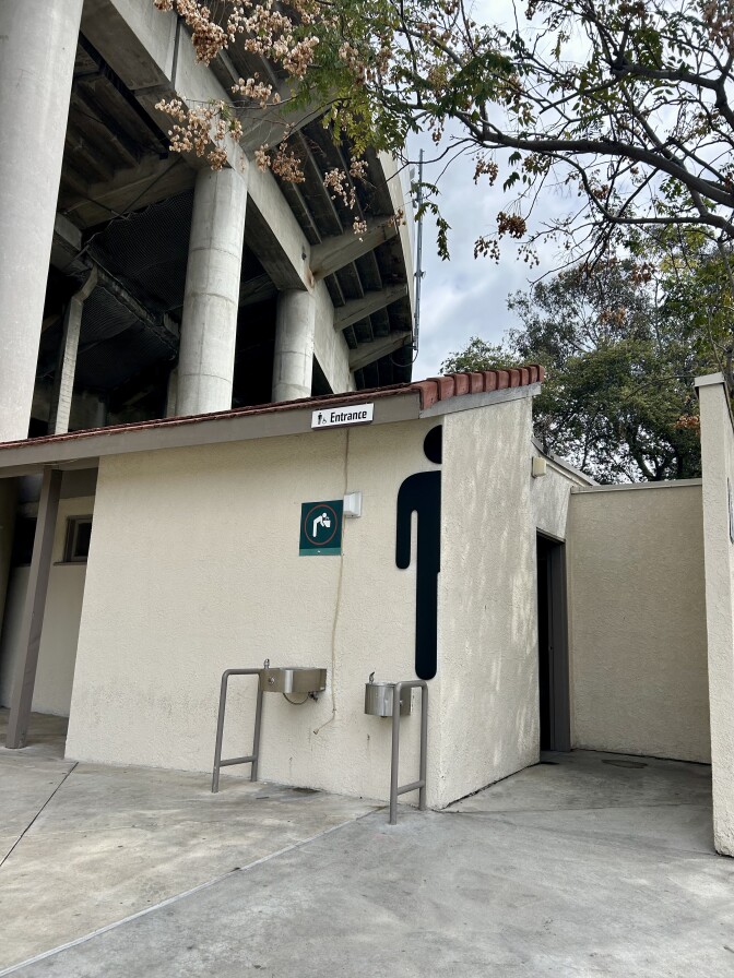 A entrance to a men's bathroom. Two drinking fountains are on a wall.