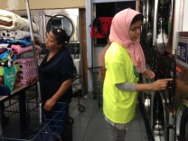A volunteer with Islamic Circle of North America Relief puts coins into a dryer for Anaheim residents during a free laundry night, sponsored by the Islamic charity group.