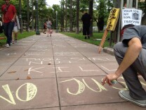 Protesters chalked slogans in front of Anaheim's City Hall on Sunday, July 21, 2013, a year after a police shooting sparked violence in the community.