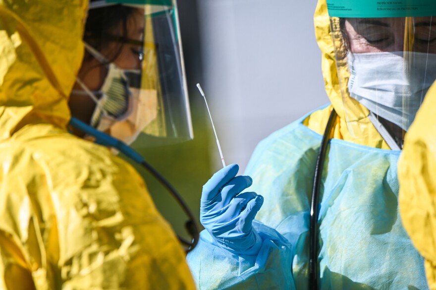 Health care workers hold a swab used for COVID-19 testing at the ProHEALTH testing site in Jericho, N.Y., Tuesday March 24, 2020.