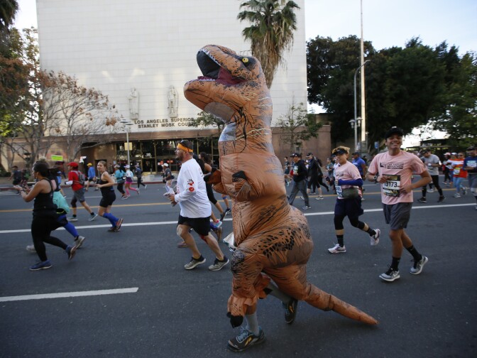 A marathon runner dressed as a T. Rex Dinosaur competes in the Los Angeles Marathon downtown Los Angeles Sunday, March 18, 2018. 