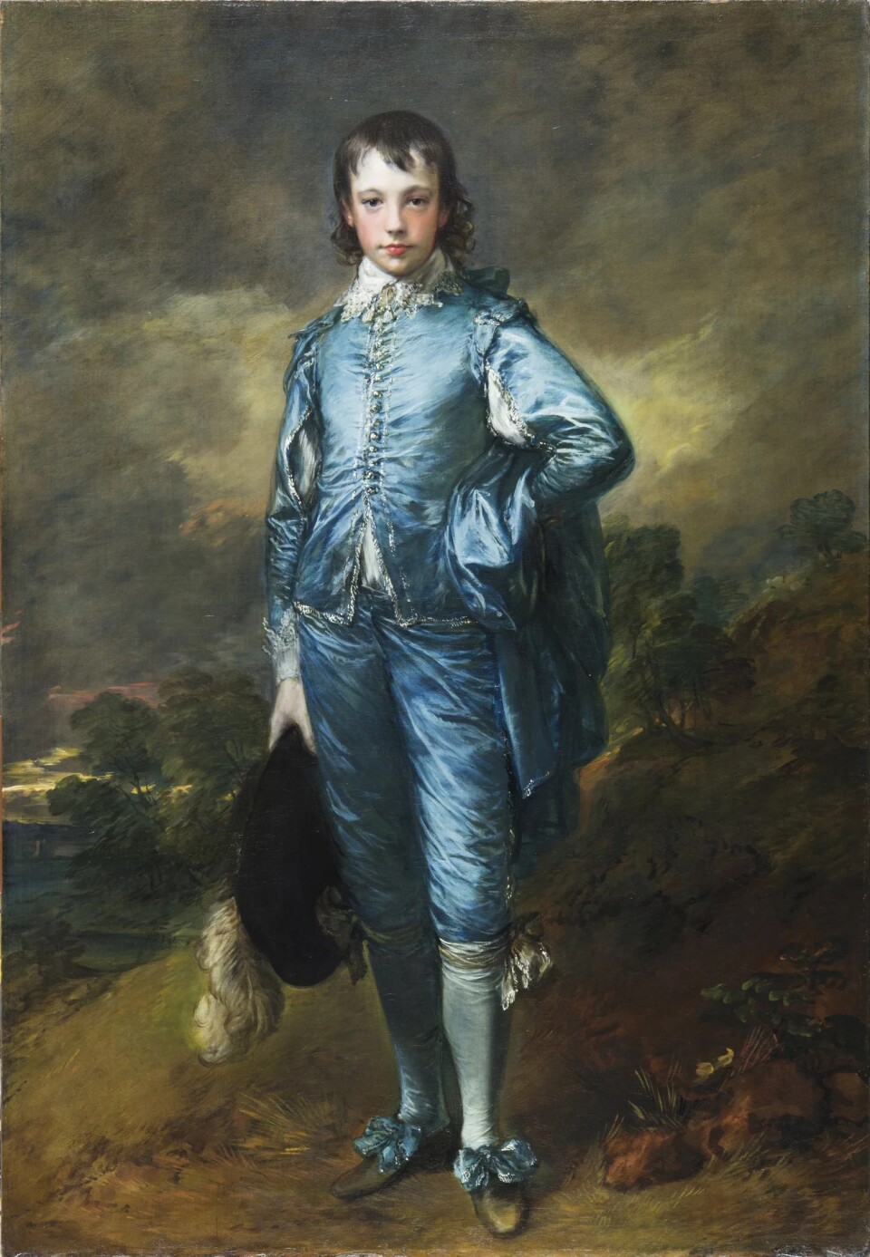The Blue Boy painting, young man from the 1700s wearing a velvet or silk light blue suit holding a feathered hat with rosy cheeks and his hand on his right hip. 