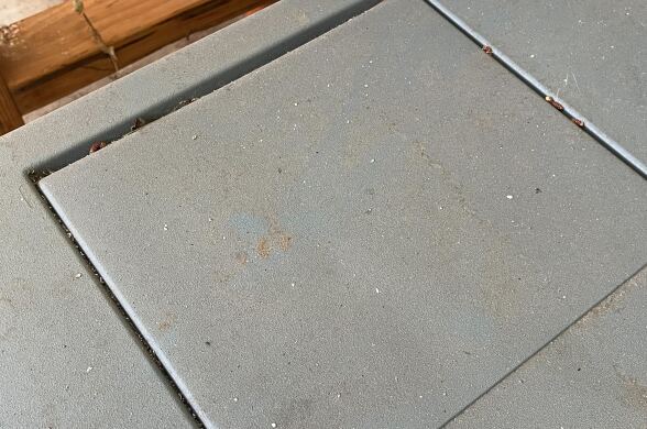 A close up of a dusty gray coolor lid that's covered in specks of ash.
