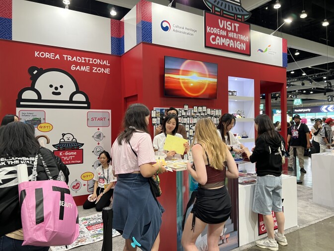 People are gathered around a red and blue exhibit that states: "Visit Korean Heritage Campaign" 