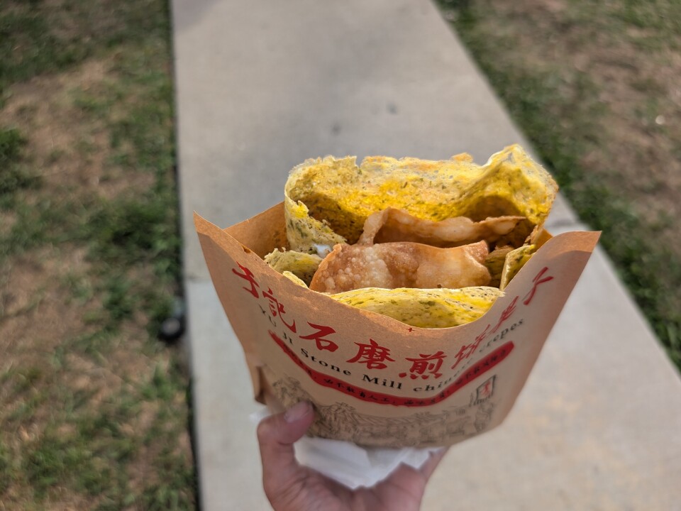 An egg wrap with a fried, crunchy dumpling wrap sticking out from inside.
