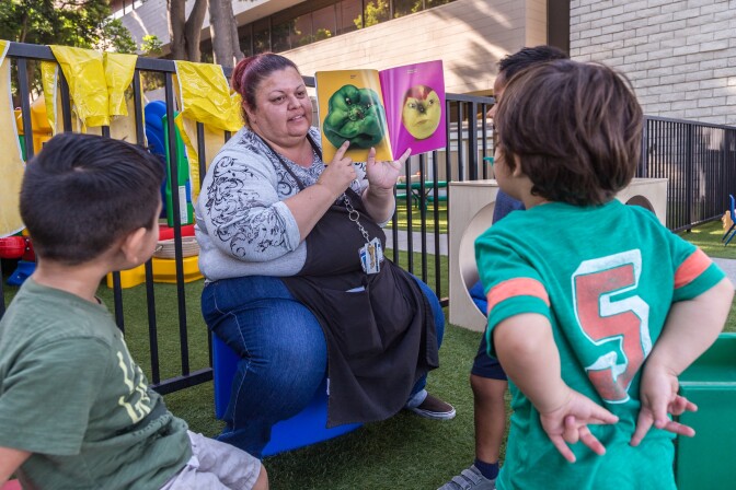 Rosa Lopez reads a book to kids at the Mexican American Opportunity Fund child care center in Norwalk. She's been in the child care field for 24 years and makes under $15/hr.