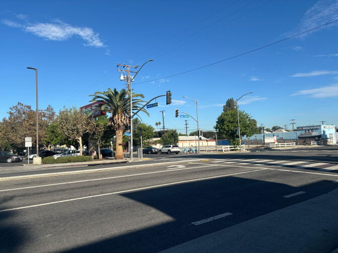 A quiet intersection with a palm tree, traffic signals, and street signs for 52nd Street and Atlantic Avenue under a clear sky.