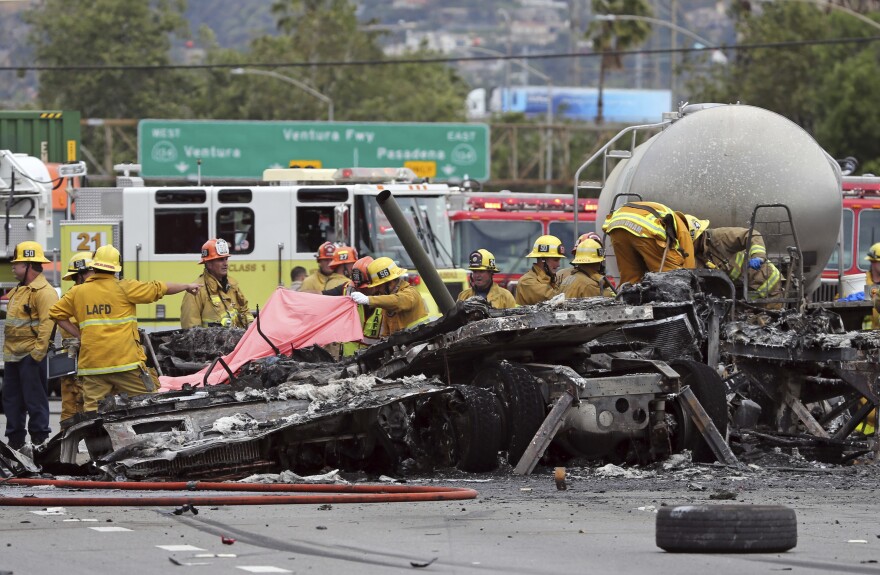 Investigators view the wreckage after a fiery collision of two big trucks and several smaller vehicles killed one person and injured several others while triggering a massive traffic jam on Interstate 5 just north of downtown Los Angeles Tuesday, April 25, 2017.  (AP Photo/Reed Saxon)