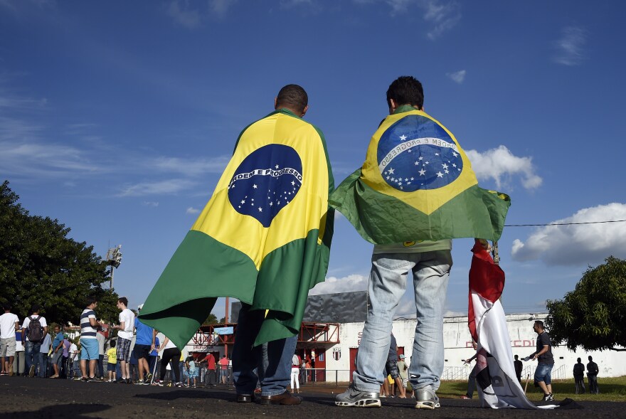 People wearing Brazilian flags arrive at the Santa Cruz Stadium in Ribeirao Prato to attend a France's national football team training session on June 10, 2014, a few days prior to the start of the 2014 FIFA World Cup in Brazil.
