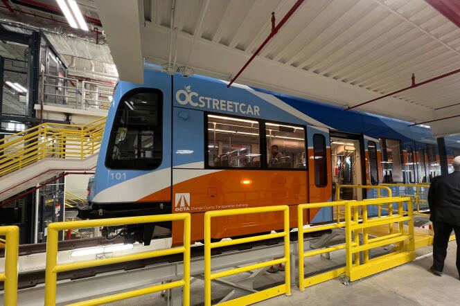 A blue and orange streetcar behind yellow barriers.