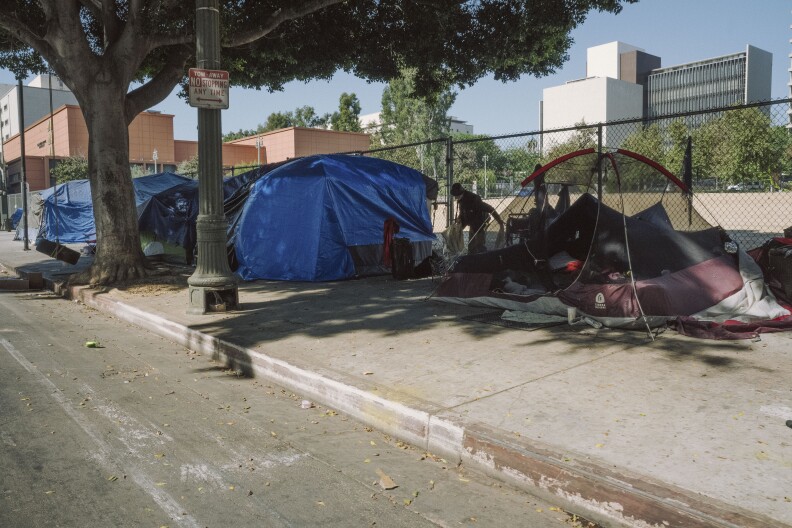 Tents on a sidewalk along a city street.
