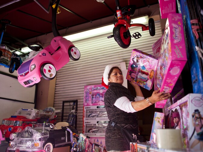 Maria Rosales puts out new merchandise in her toy store in Santee Alley as shoppers buy last-minute gifts on Christmas Eve.