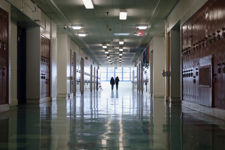 A long hallway with bright windows at the end and lockers.