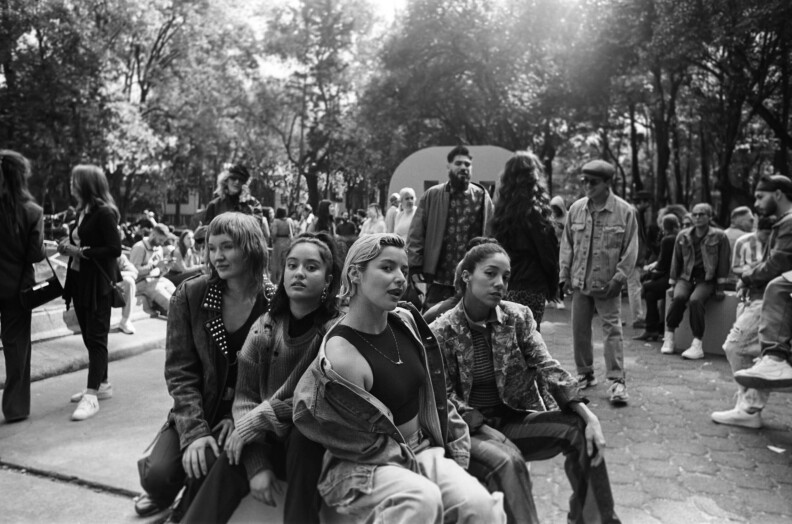 Fotografía en blanco y negro de varias personas posando para la cámara en lo que parece ser un concurrido parque público.