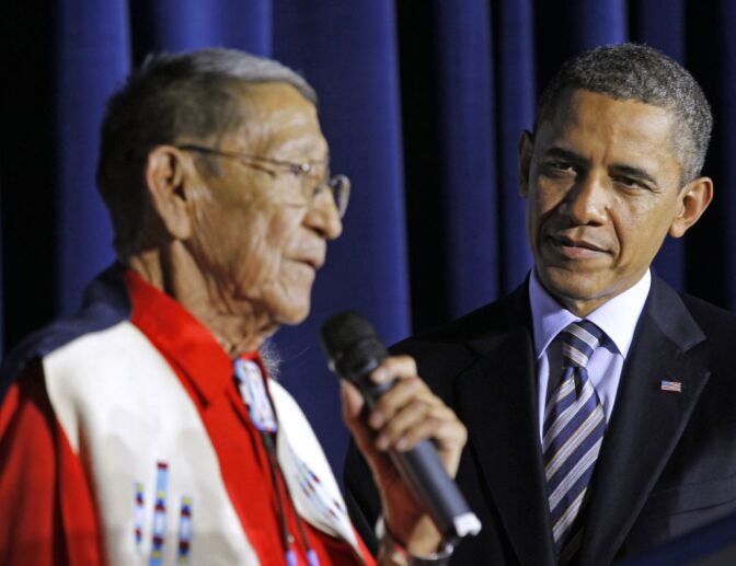 President Barack Obama listens as Hartford “Sonny” Black Eagle delivers remarks at the White House Tribal Nations Conference at the Interior Department in Washington. Native American tribal leaders are concerned that steady progress on their issues might be undermined if President Barack Obama and Congress make deep spending cuts in order to avoid the “fiscal cliff.” More than 500 tribal leaders were taking those concerns to the fourth White House Tribal Nations summit, which convenes Wednesday, Dec. 5, 2012. Obama is scheduled to address the group in the afternoon.  