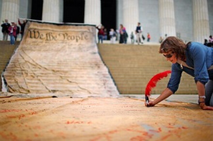 A woman signs a giant banner printed with the Preamble to the United States Constitution during a demonstration against the Supreme Court's Citizens United ruling at the Lincoln Memorial.