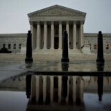 The US Supreme Court building is reflected in water.