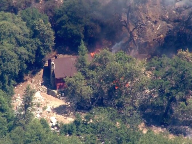 A screenshot of the Cabin Fire burning in Angeles National Forest shows a structure in flames. 