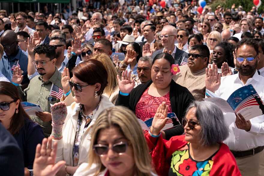 A large group of people, each holding up their right hand