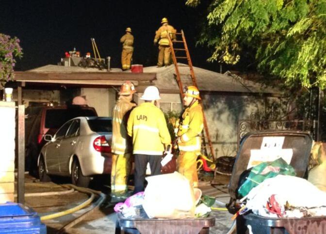 Firefighters outside a Pacoima home that was damaged in a fire Saturday, Jan. 3, 2015.