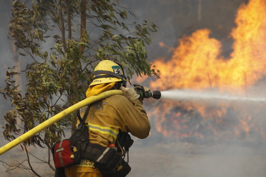 SAN MARCOS, CA - MAY 15:  A firefighter hoses flames at the Cocos fire on May 15, 2014 in San Marcos, California. Fire agencies throughout the state are scrambling to prepare for what is expected to be a dangerous year of wildfires in this third year of extreme drought in California.   (Photo by David McNew/Getty Images)
