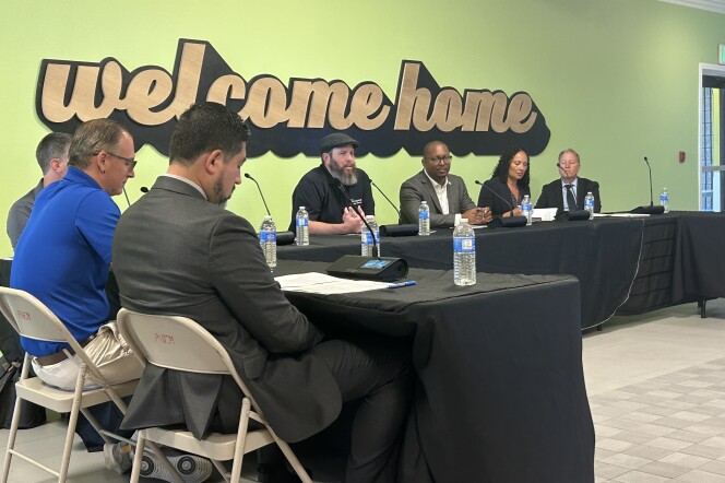 People sitting around tables in front of a graphic that says 'welcome home'