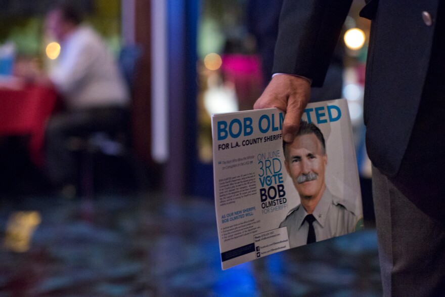 A supporter holds flyers for Los Angeles County Sheriff candidate Bob Olmsted during his election gathering at Pierre Garden in Glendale on Tuesday night, June 3.