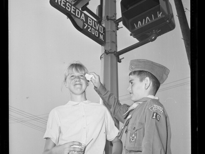 Jeffrey La France, a Reseda boy scout, helps Nancy Rayder, 11, dry her eyes during four-hour smog alert called in Reseda on October 7, 1965. 