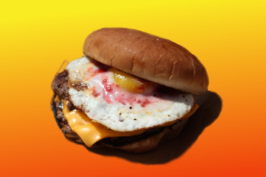 two burger patties with American cheese, an egg and raspberry jam on a bun