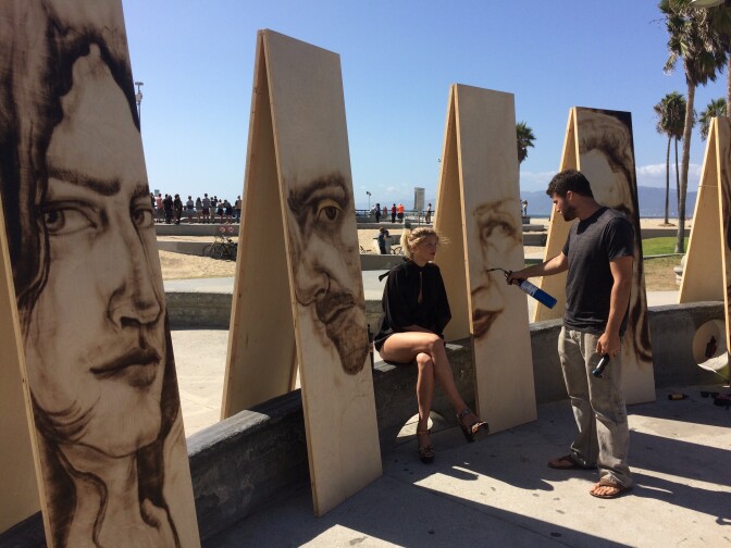 Zachary Aronson works on a portrait of Tazi Apple on the Venice Boardwalk. 