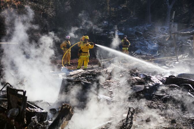 File: Firefighters work to contain embers on the remains of a house destroyed by the Clayton Fire in Lower Lake, California. 