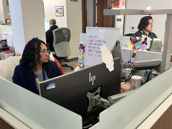  Workers at office cubicles are looking at computer screens, responding to calls for homeless services at the L.A. County Emergency Centralized Response Center. 
